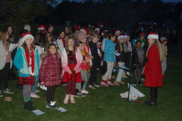 Stacey Ferris conducts the Eddy School Choir in holiday carols beneath the freshly lit Christmas tree at Drummer Boy Park.