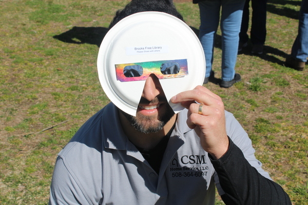 Claudson Moraes of Harwich views the eclipse with paper plate viewing glasses prepared by the library staff.