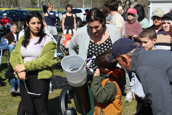 Tom Leach of the Cape Cod Astronomical Society assists people in viewing the eclipse through a solar scope provided by the Harwich Observatory.